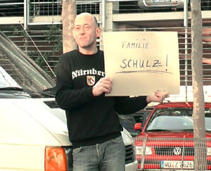 Ein Mann steht am Flughafen mit einem Schild auf dem steht “Familie Schulz“ ©Jugendhaus Bertha